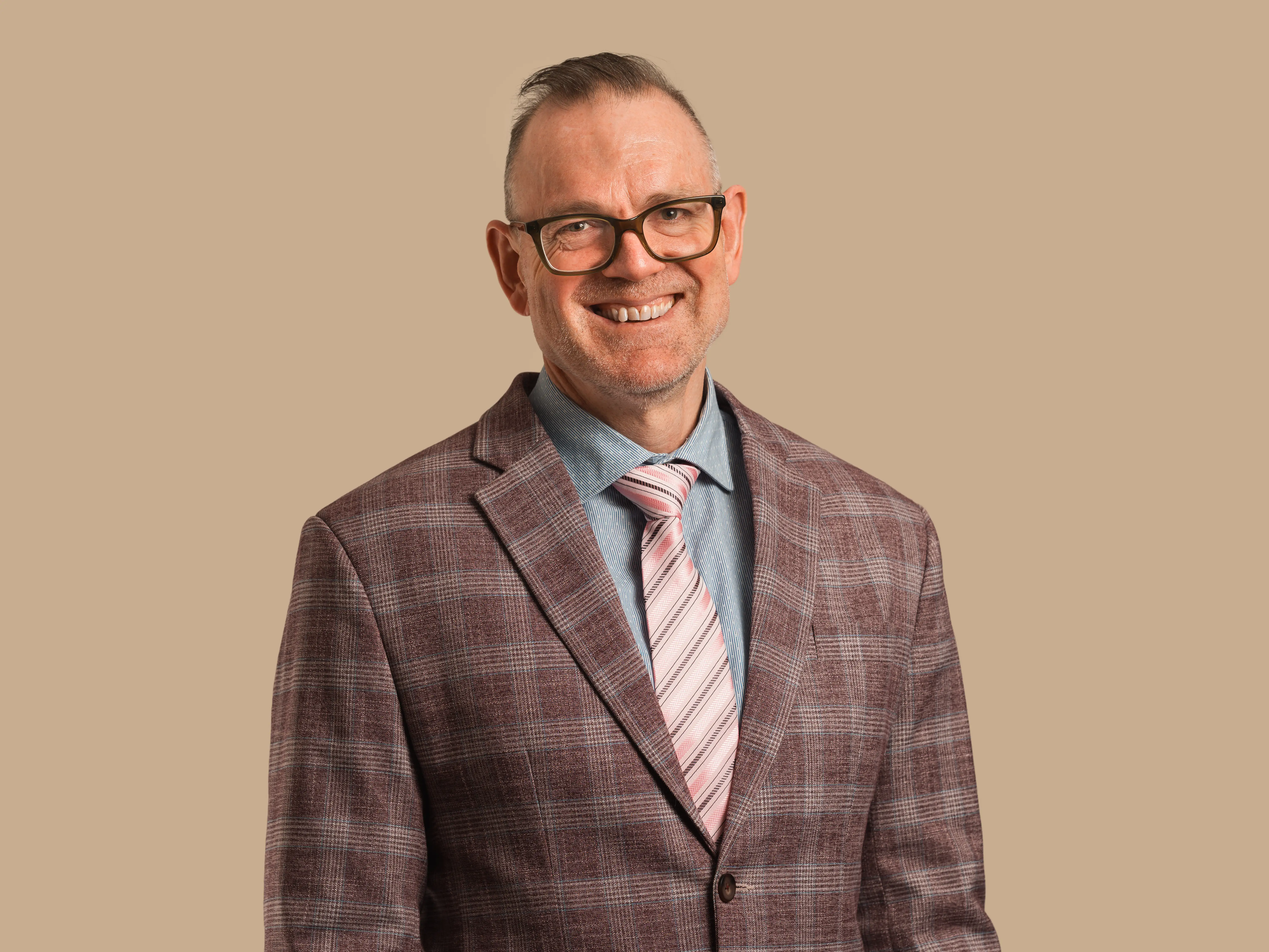 Scott wears glasses and a patterned suit