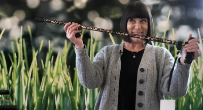 LEsley is an elderly lady with ear-length short black hair. She holds up a funky cheetah print walking stick.