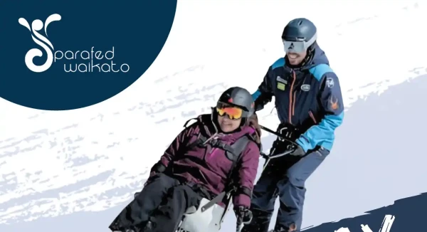 A Whakapapa instructor and a young participant girl carve through the snow together on adaptive ski equipment.