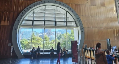 On the right, the Te Papa help desk offers two levels for standing and wheelchair users. In the middle, a large circular window frames people standing around.