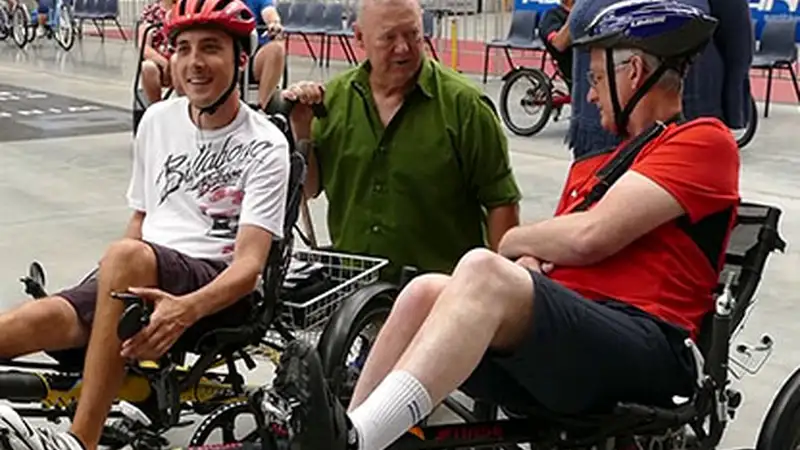 Three male members of the trike group chat on their three wheeled bikes