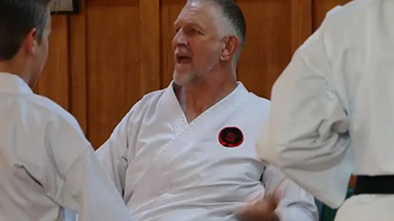 John Marble is a middle aged European. He uses a wheelchair and sports his karate uniform.