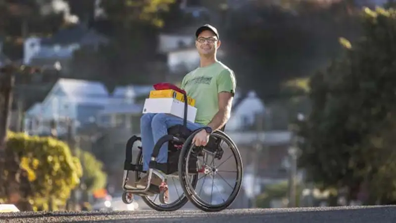 Mke Brown is a Māori man who uses a wheelchair. He's currently balancing on the back of his two wheels.