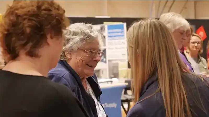 A woman with blonde hair helps and elderly lady.