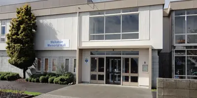 Waikanae Memorial Hall is a spacious building with a white and brown exterior, featuring three large push-and-pull doors at the front.